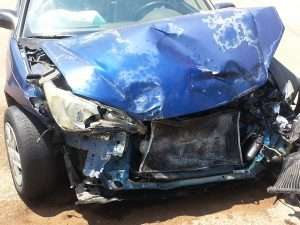 A damaged blue car with the front smashed in after a car accident.